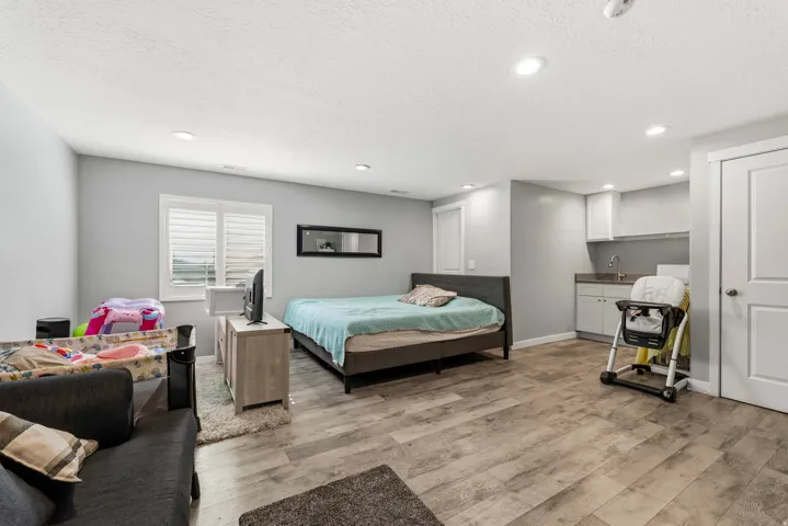Spacious room featuring wood-finish flooring, recessed lighting, and a window with plantation shutters