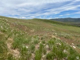 Expansive open land featuring rolling hills and distant mountains under a broad sky