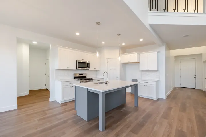 Spacious kitchen with a central island, stainless steel appliances, white cabinetry, and wood-finish flooring