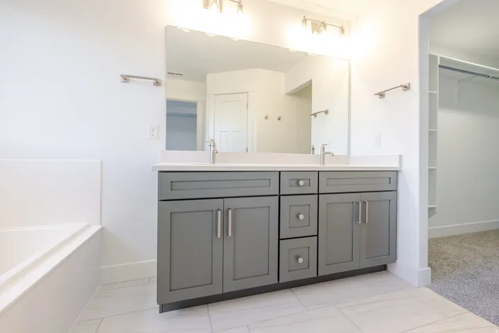 Dual vanity with gray cabinetry, white countertop, and integrated sinks