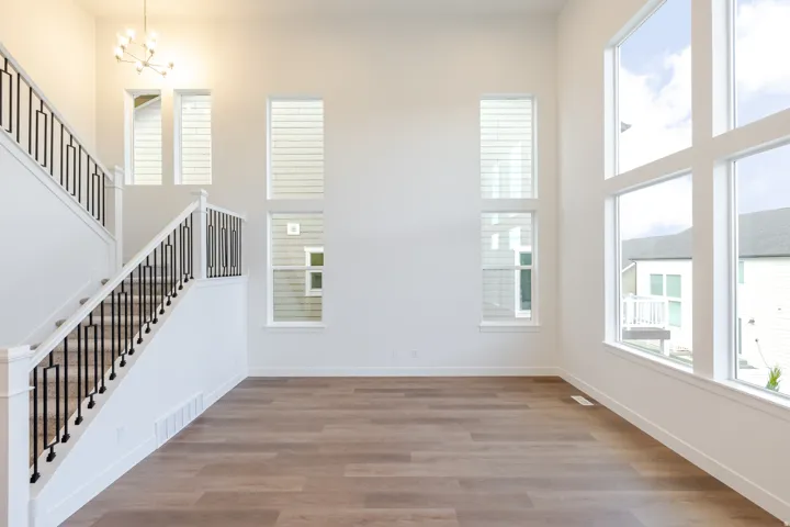 Vaulted ceiling with a contemporary chandelier, wood-finish flooring, and multiple vertical windows