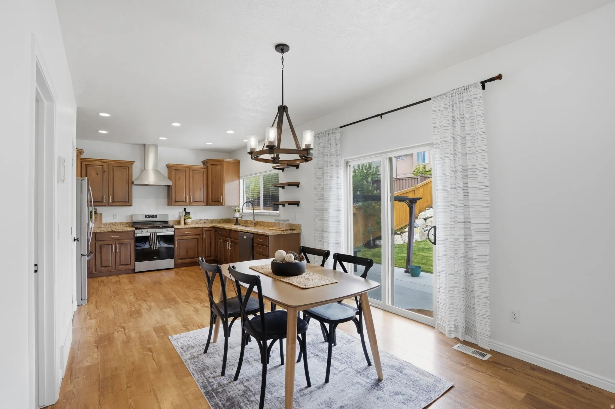 Open-concept dining area featuring wood-finish flooring, a modern chandelier, and direct access to the outdoor space via sliding glass doors