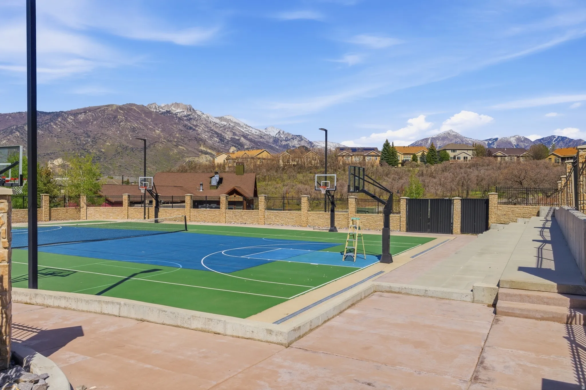 Multi-sport court featuring a vibrant blue and green surface with basketball hoops and a tennis net