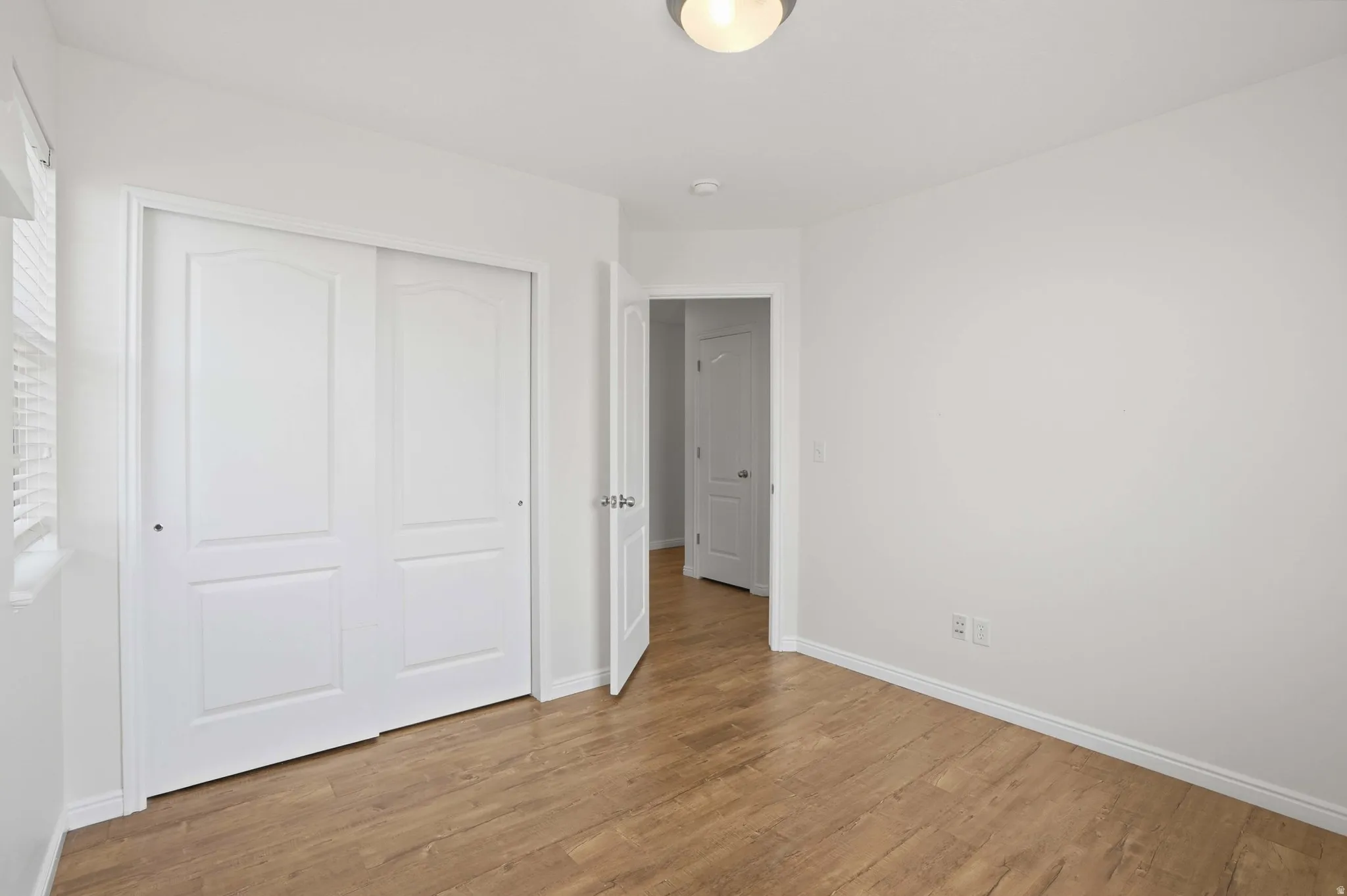 White interior room featuring wood-finish flooring, white baseboards, and a semi-flush mount ceiling light fixture