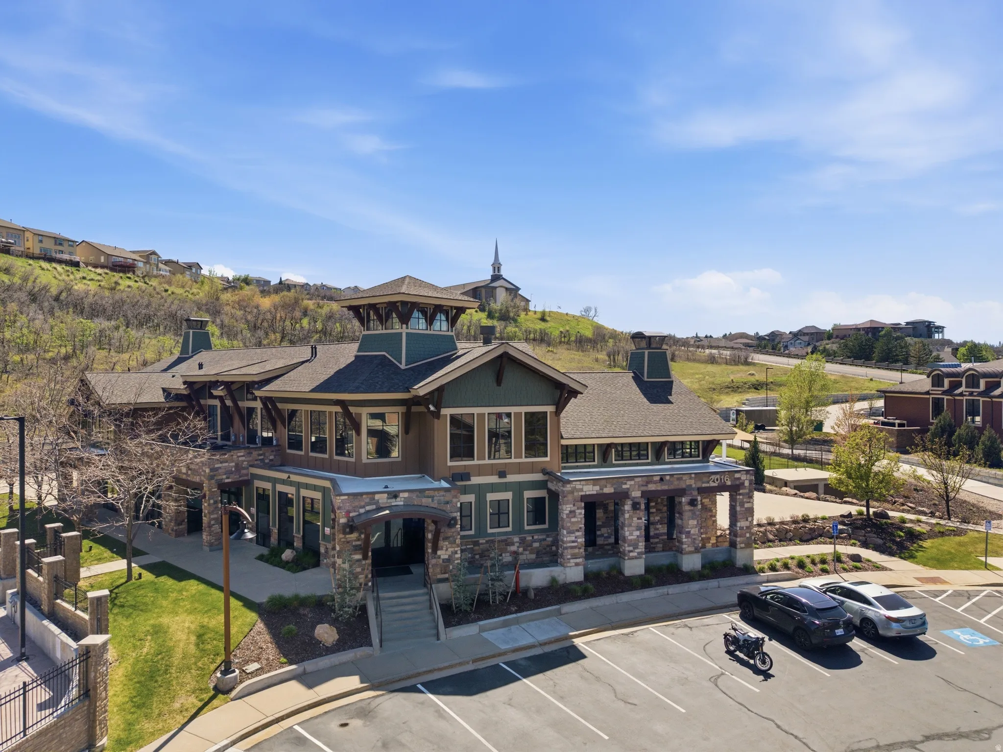 Multi-level building featuring stone and wood-finish siding, a prominent central cupola, and a gabled roofline