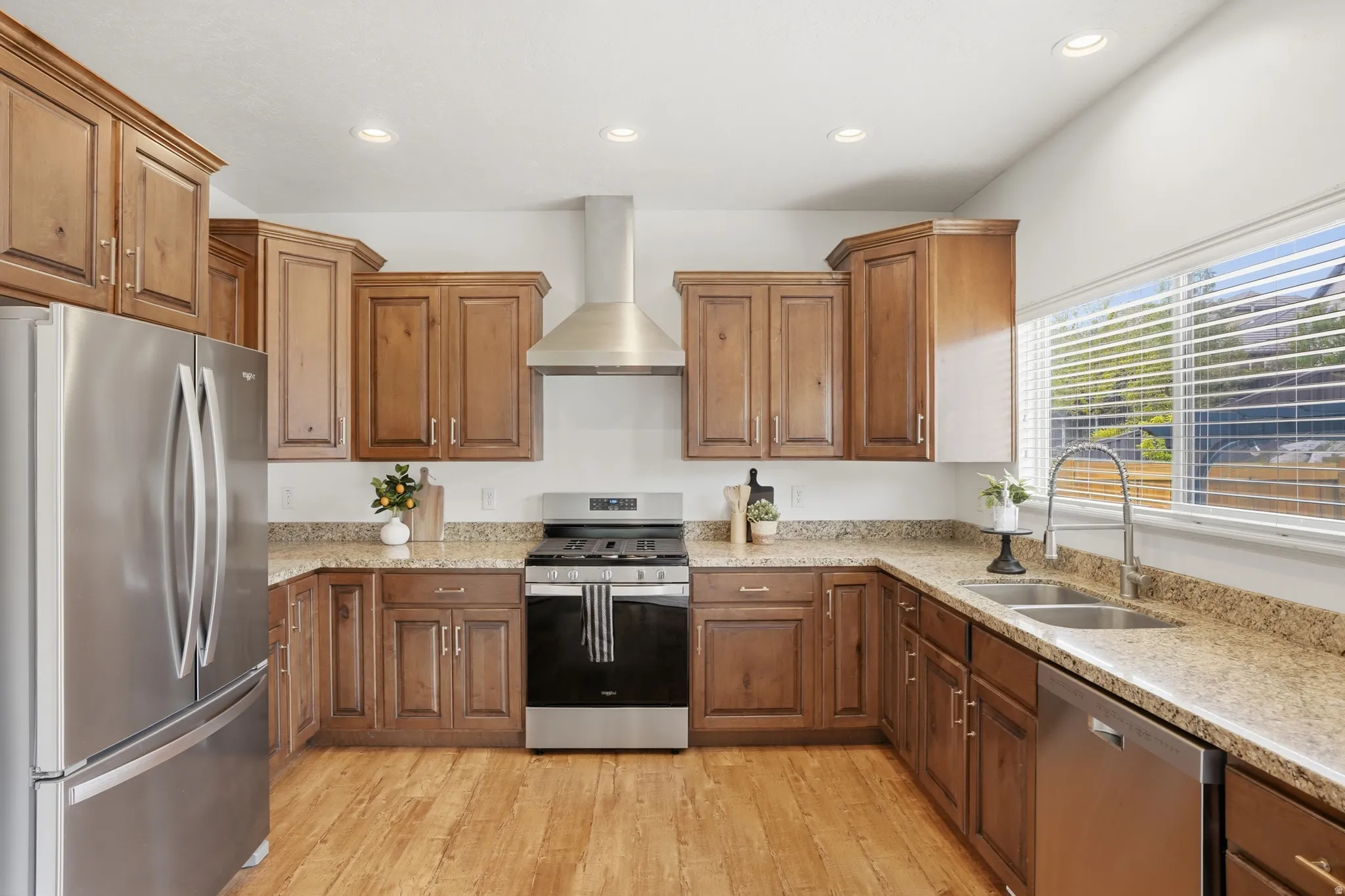 Kitchen featuring wood-finish flooring, stainless steel appliances, granite-style countertops, wood cabinetry, and recessed lighting