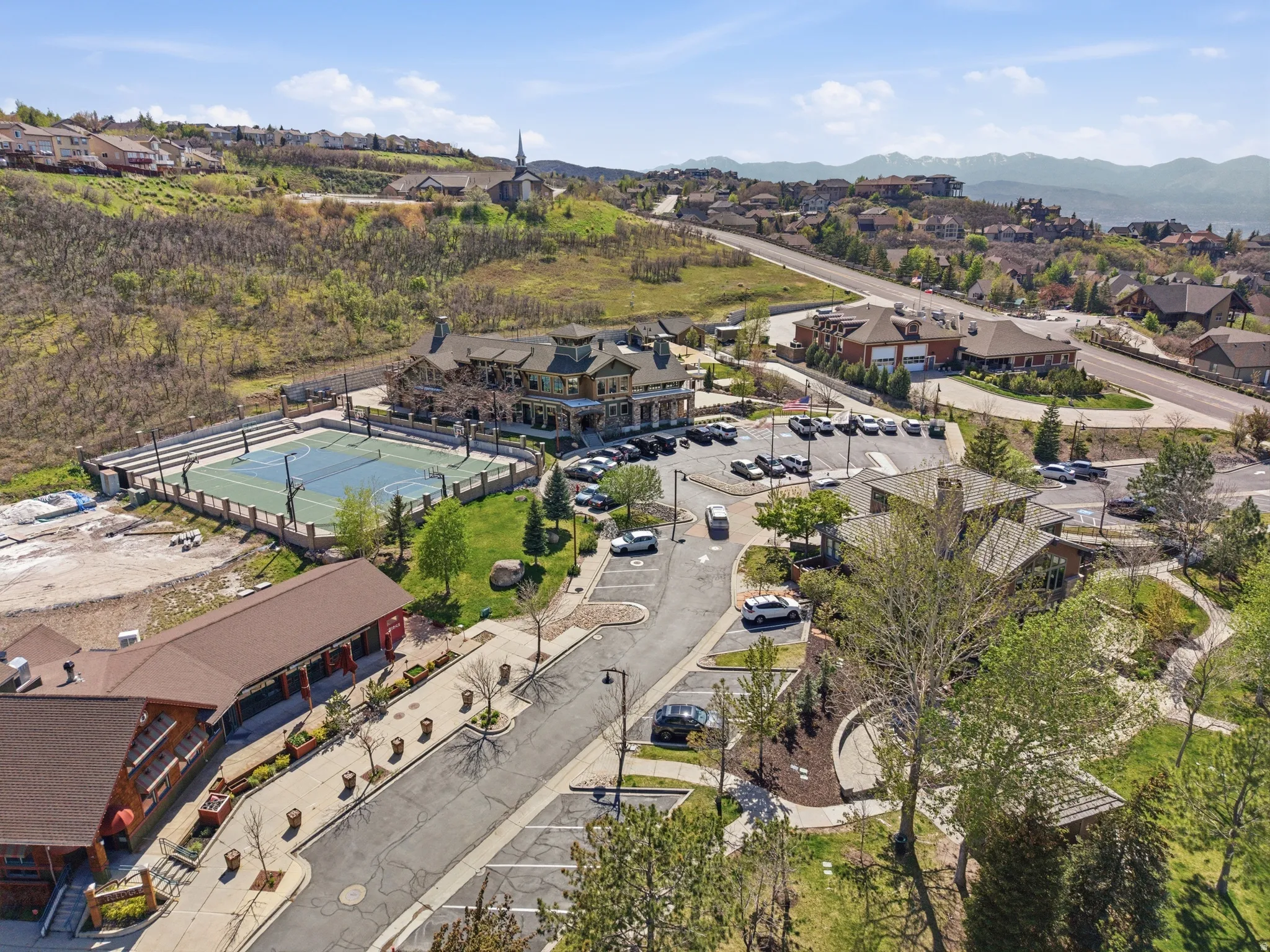 Aerial perspective showcasing multiple buildings, a sports court, and paved parking areas