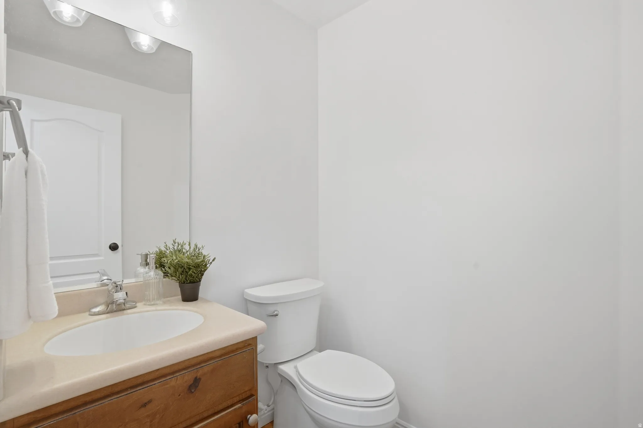 Bathroom featuring a single vanity with a wood-finish cabinet, integrated sink, and a light-toned countertop