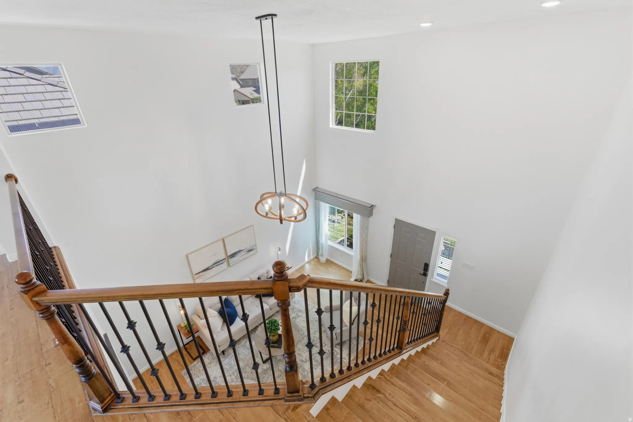 Two-story foyer featuring a contemporary chandelier, hardwood flooring, and wrought iron balusters