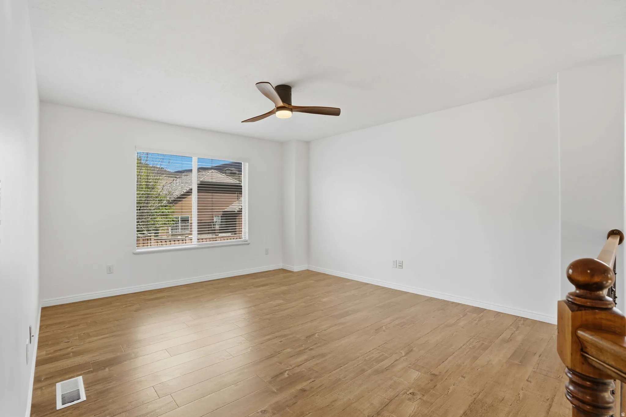 Spacious room with wood-finish flooring and a contemporary ceiling fan