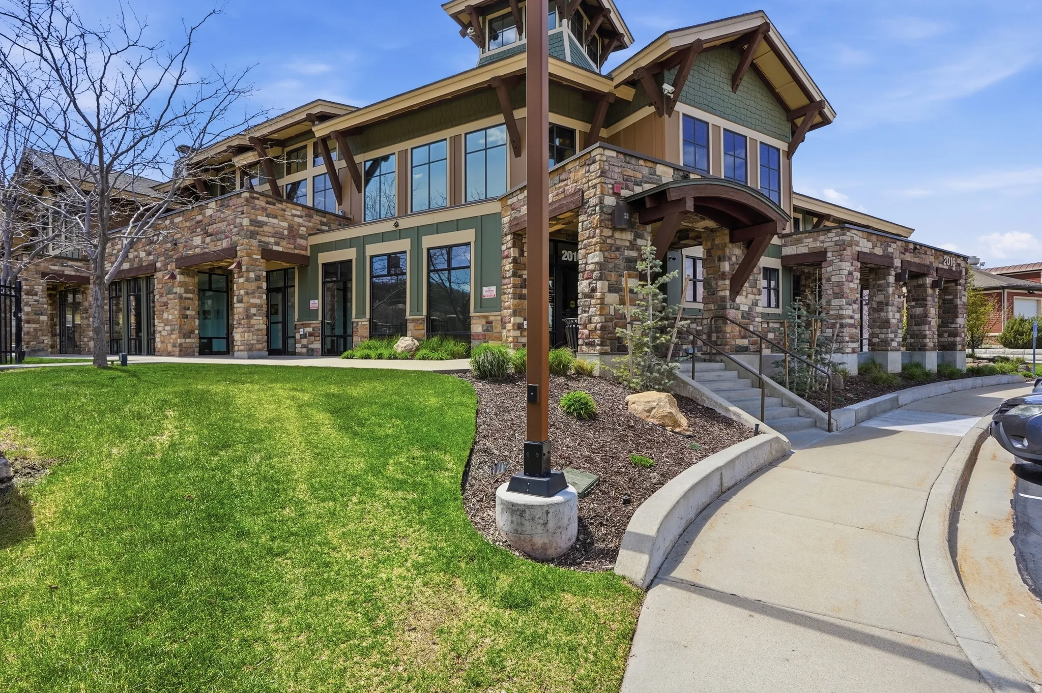 Stone and wood-finish exterior with large windows, a prominent entryway, and a manicured lawn