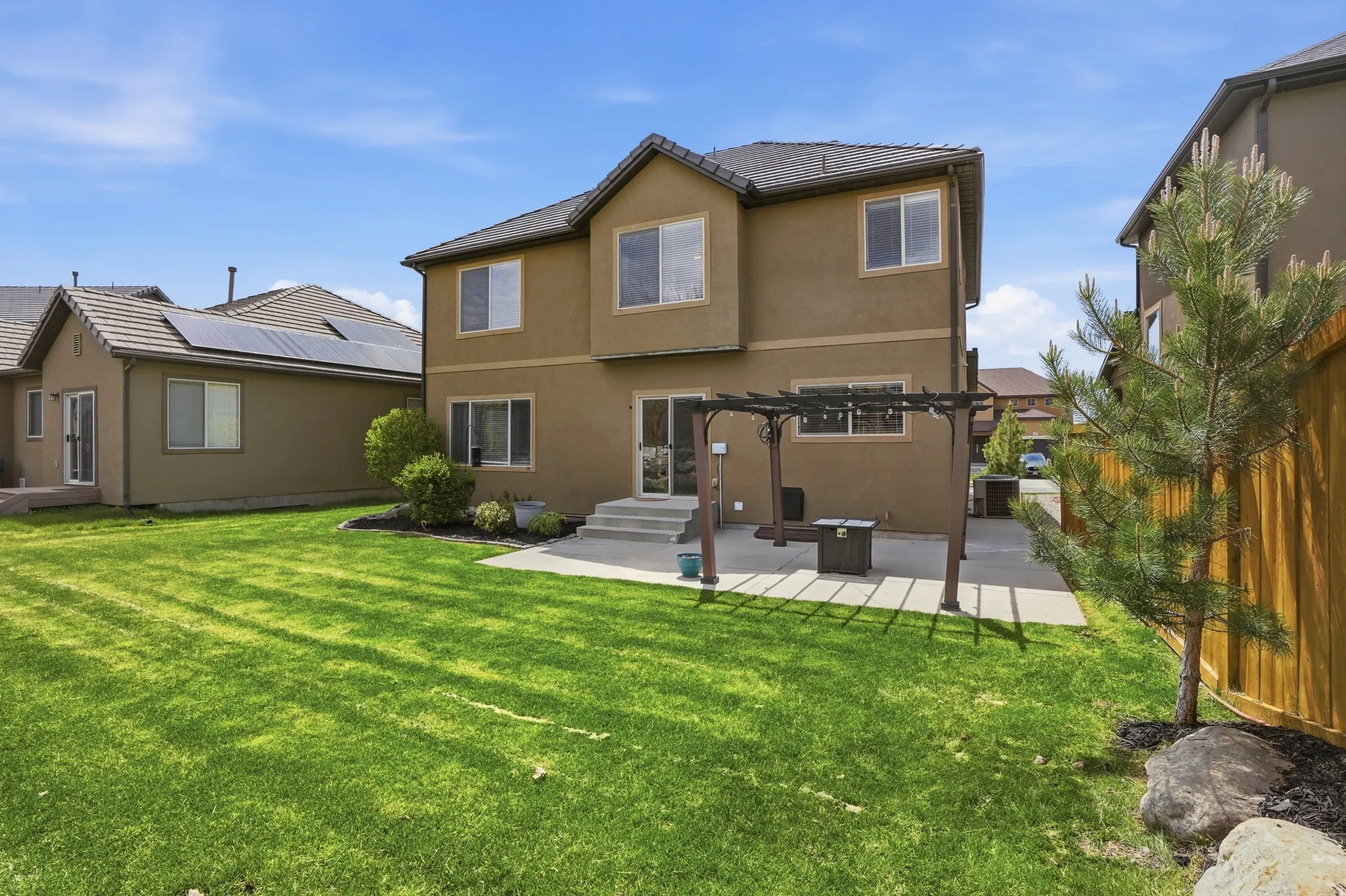 Expansive backyard featuring a large green lawn and a stone patio