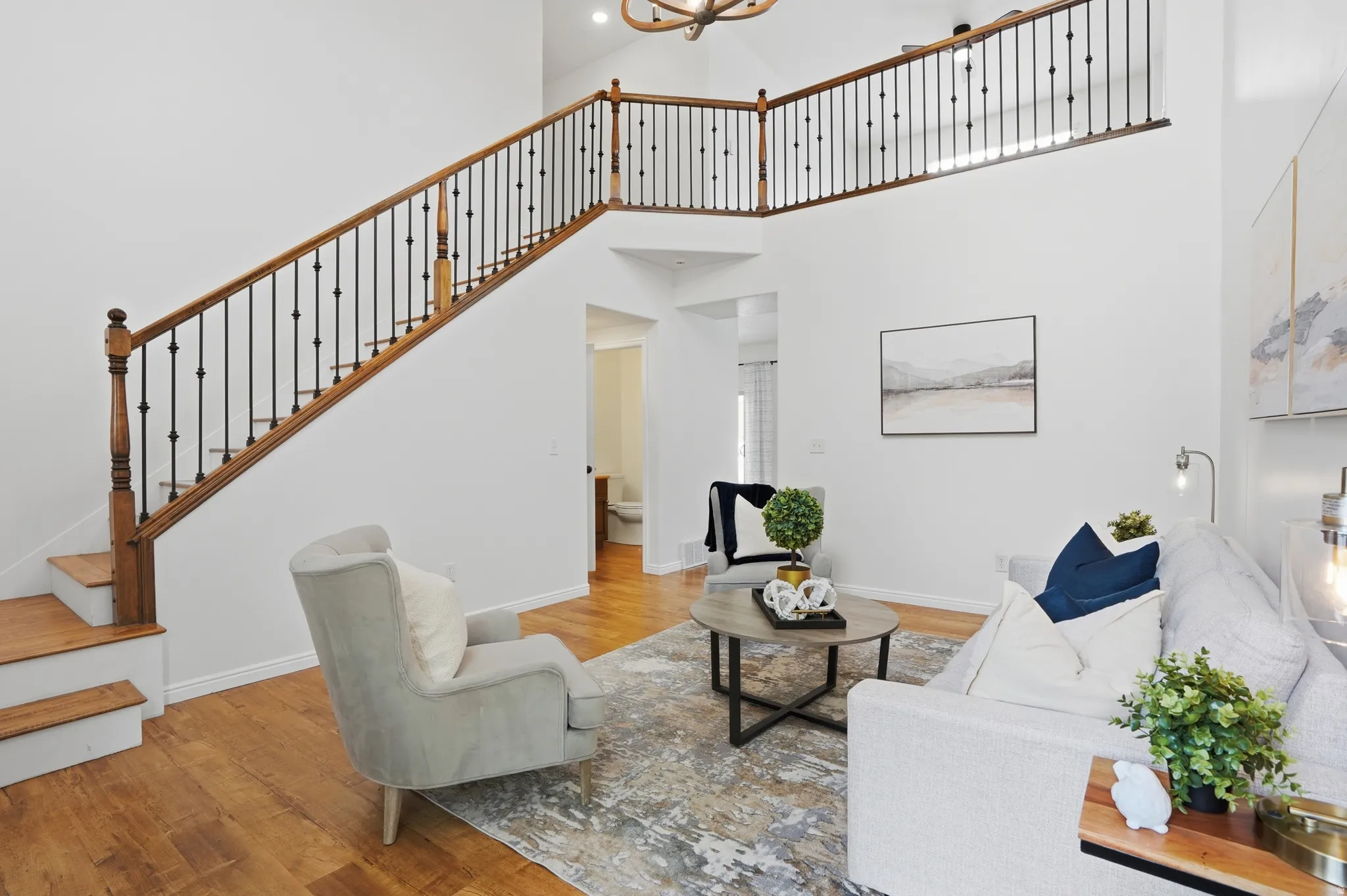 Two-story foyer with wood-finish flooring and a staircase featuring a wood handrail with wrought iron balusters