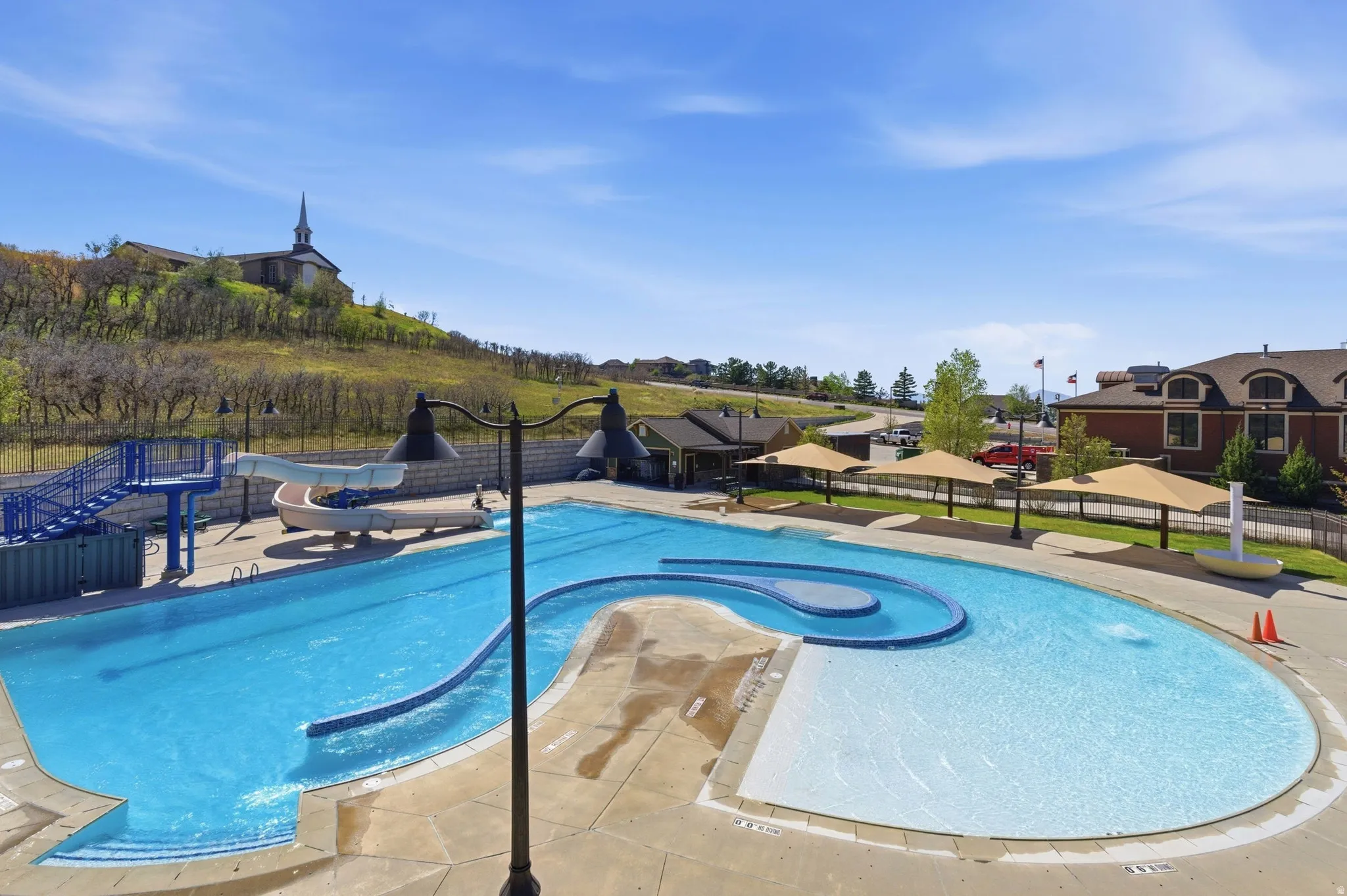 Outdoor pool complex featuring a large swimming pool with a distinct lazy river section, an integrated splash pad, and multiple water slides