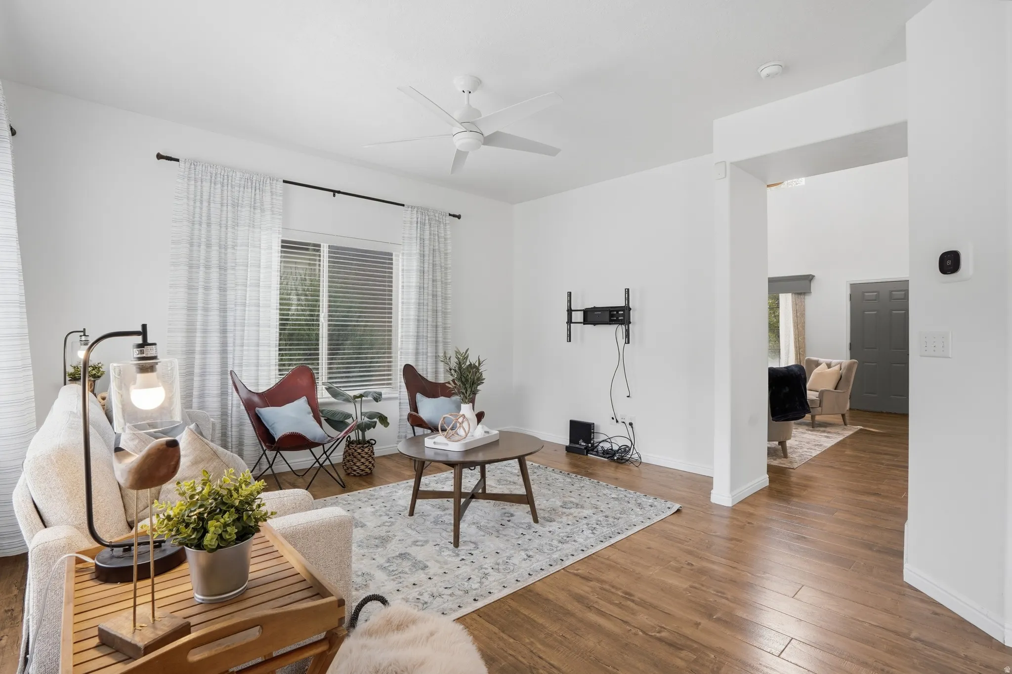 Spacious living area featuring wood-finish flooring, a ceiling fan, and white walls