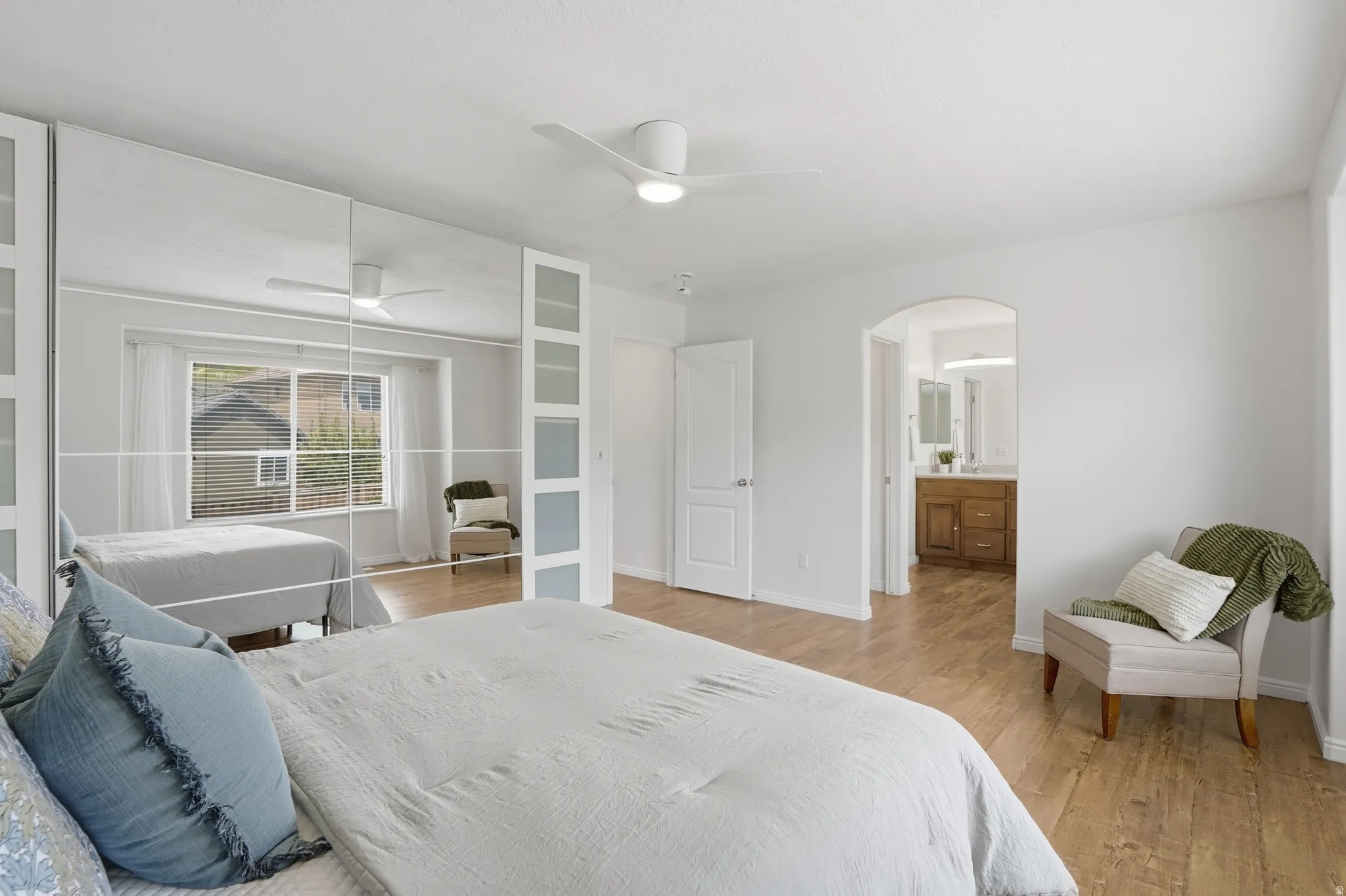 Bedroom featuring wood-finish flooring, a contemporary ceiling fan, and mirrored closet doors