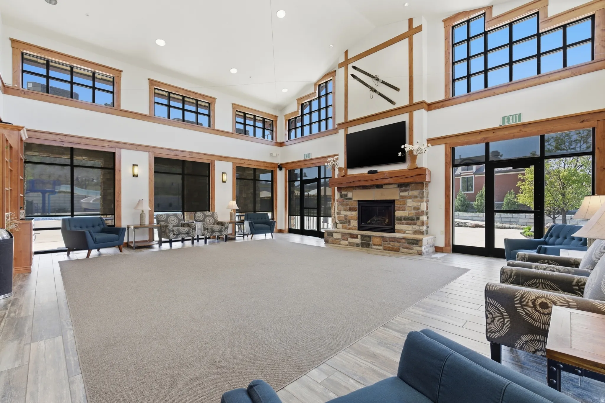 Spacious common area featuring a stone fireplace with a wood mantle, high ceilings, and large windows