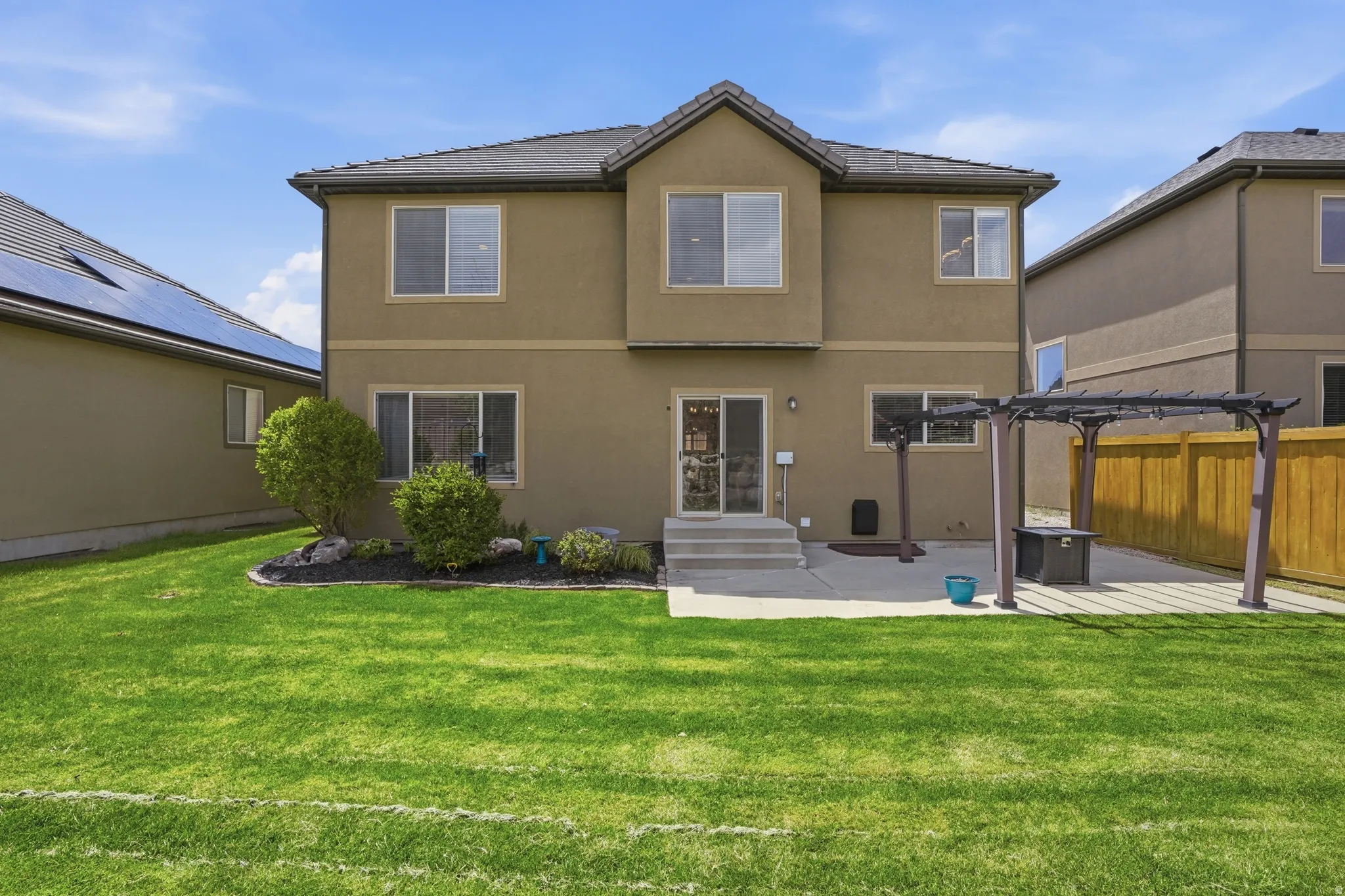Expansive green lawn with a concrete patio featuring a pergola