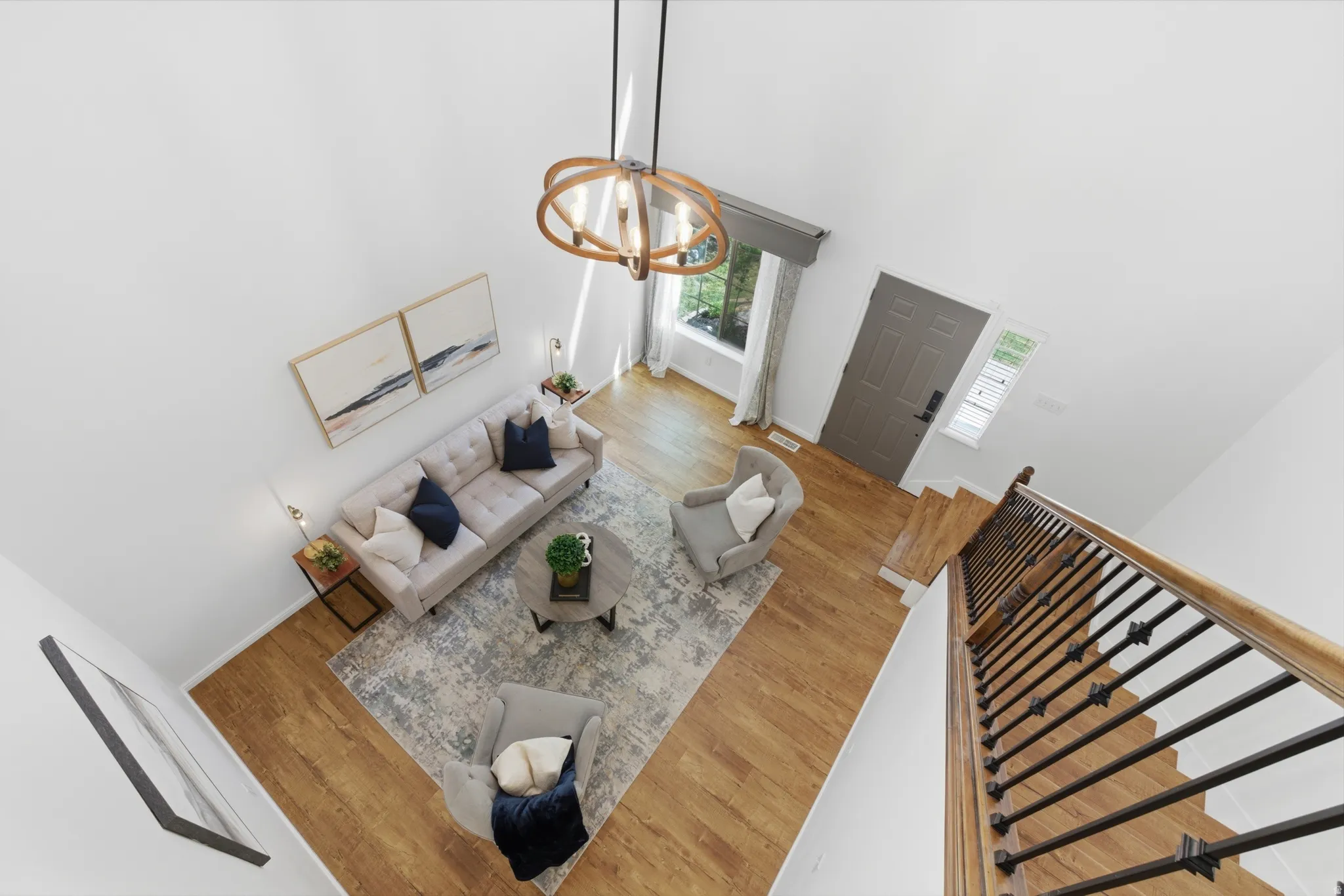 Double-height ceiling living area featuring wood-finish flooring and a contemporary chandelier