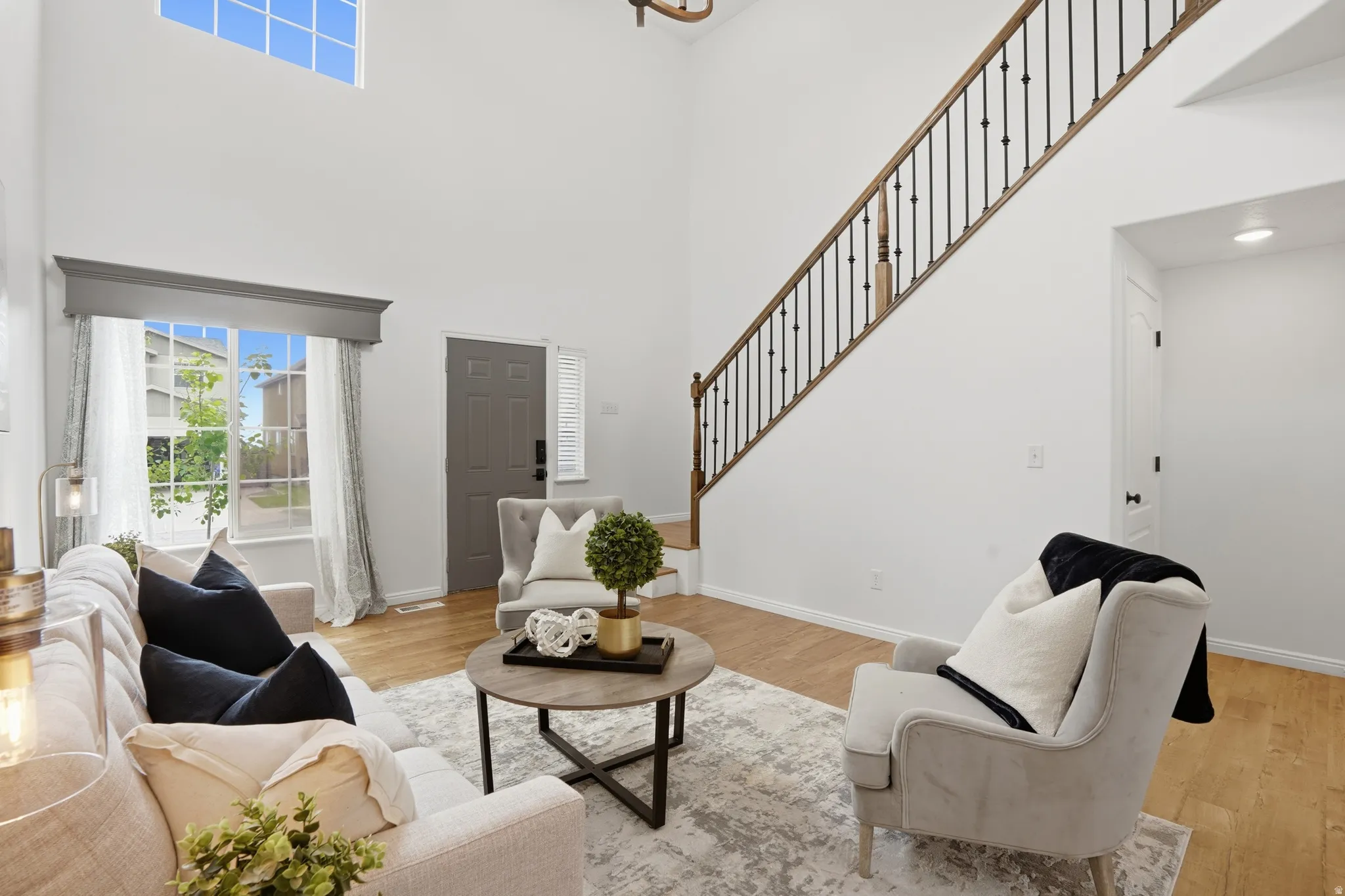 Two-story living area featuring a prominent staircase with dark metal balusters and wood handrails