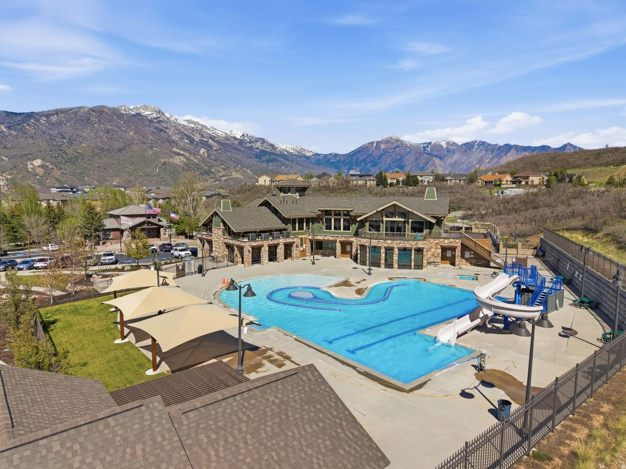 Community aquatic center featuring a large swimming pool, water slides, and shade structures