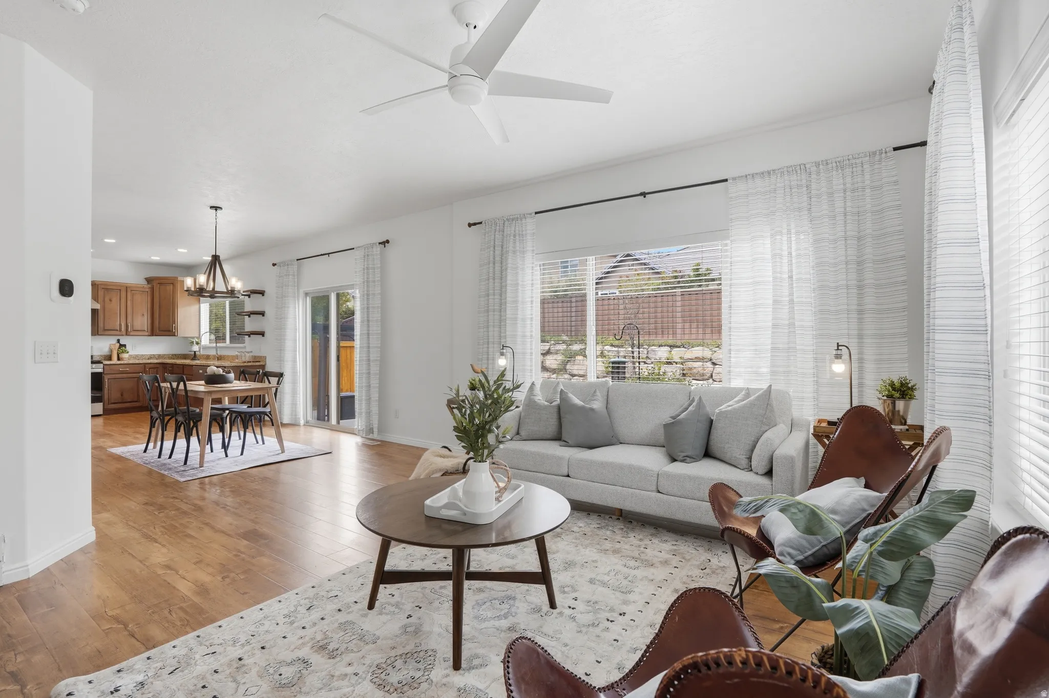 Open-concept living space featuring wood-finish flooring, a white ceiling fan, and sliding glass door access to the exterior