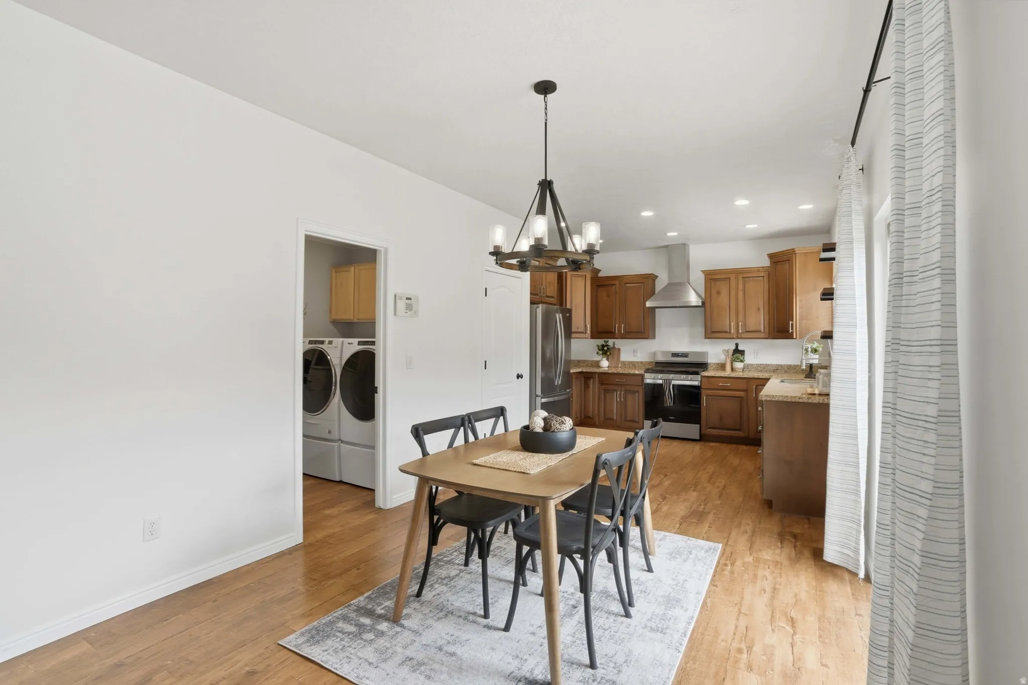 Kitchen and dining area featuring wood-finish flooring, recessed lighting, and a modern chandelier