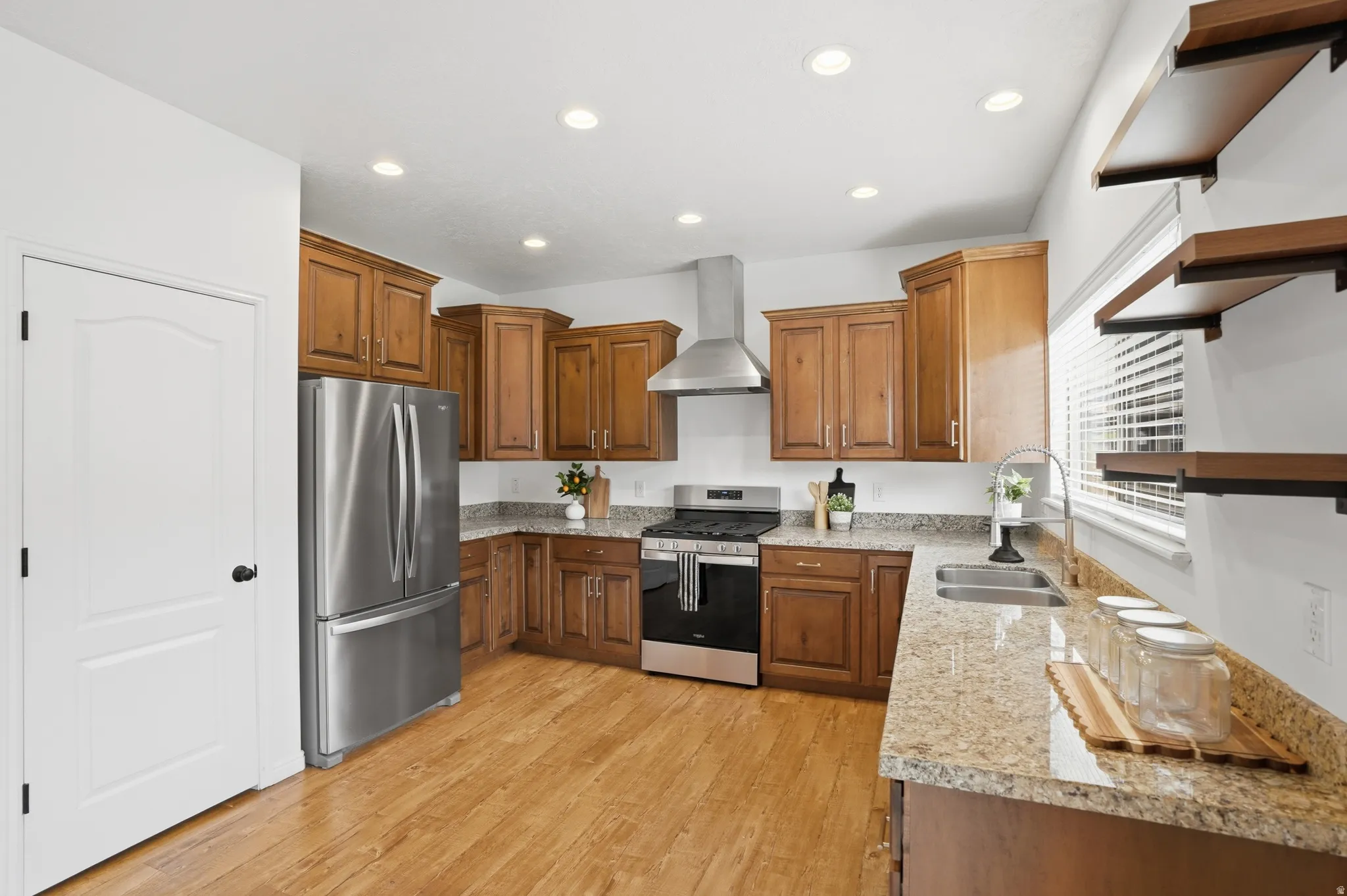 Full kitchen with wood-finish flooring, stainless steel appliances, abundant cabinetry, stone countertops, and recessed lighting