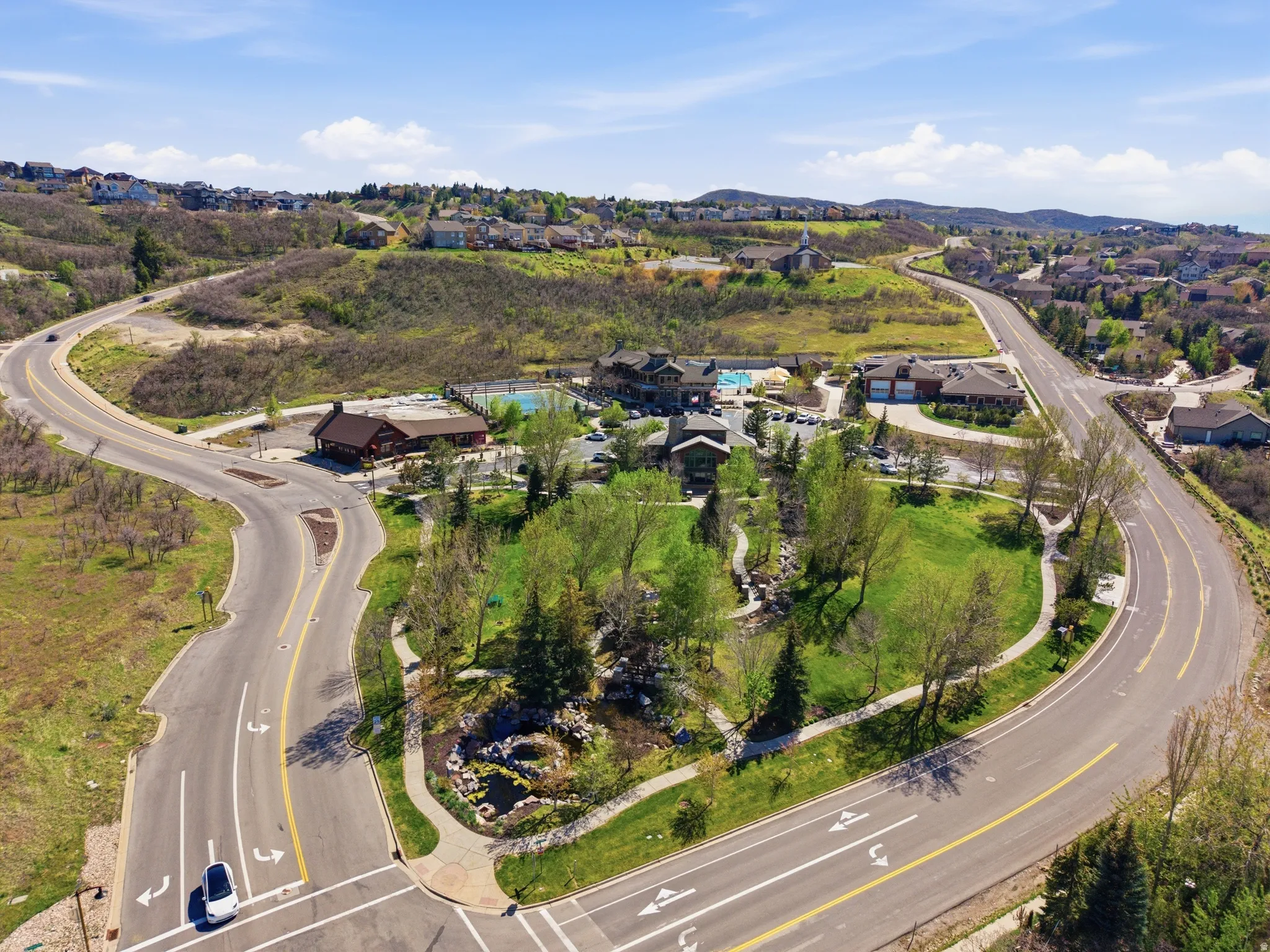 Aerial perspective showcasing a community park with mature trees, green spaces, and paved pathways