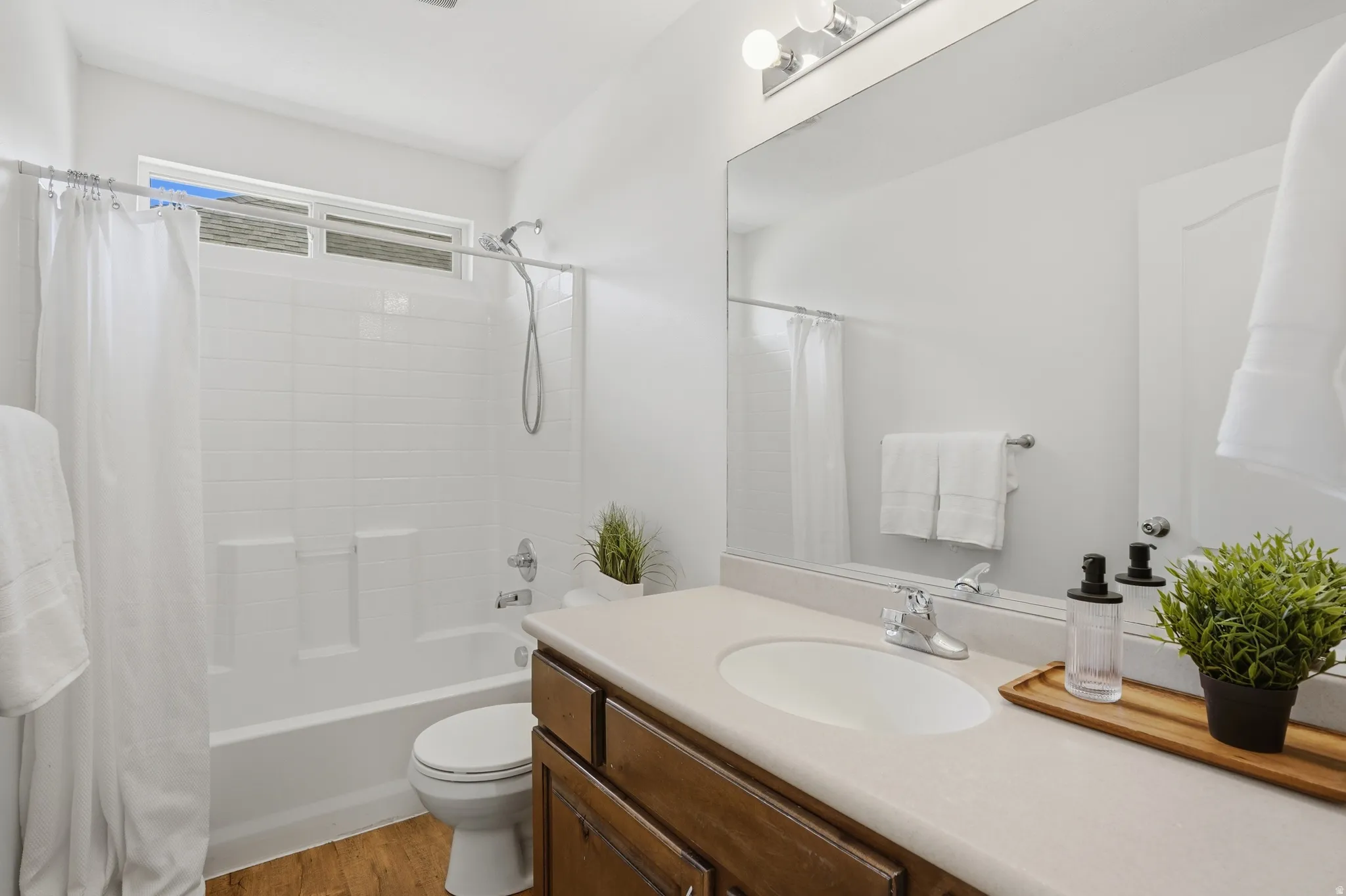 Bathroom featuring a single vanity with wood-finish cabinetry, an integrated sink, and a large wall-mounted mirror