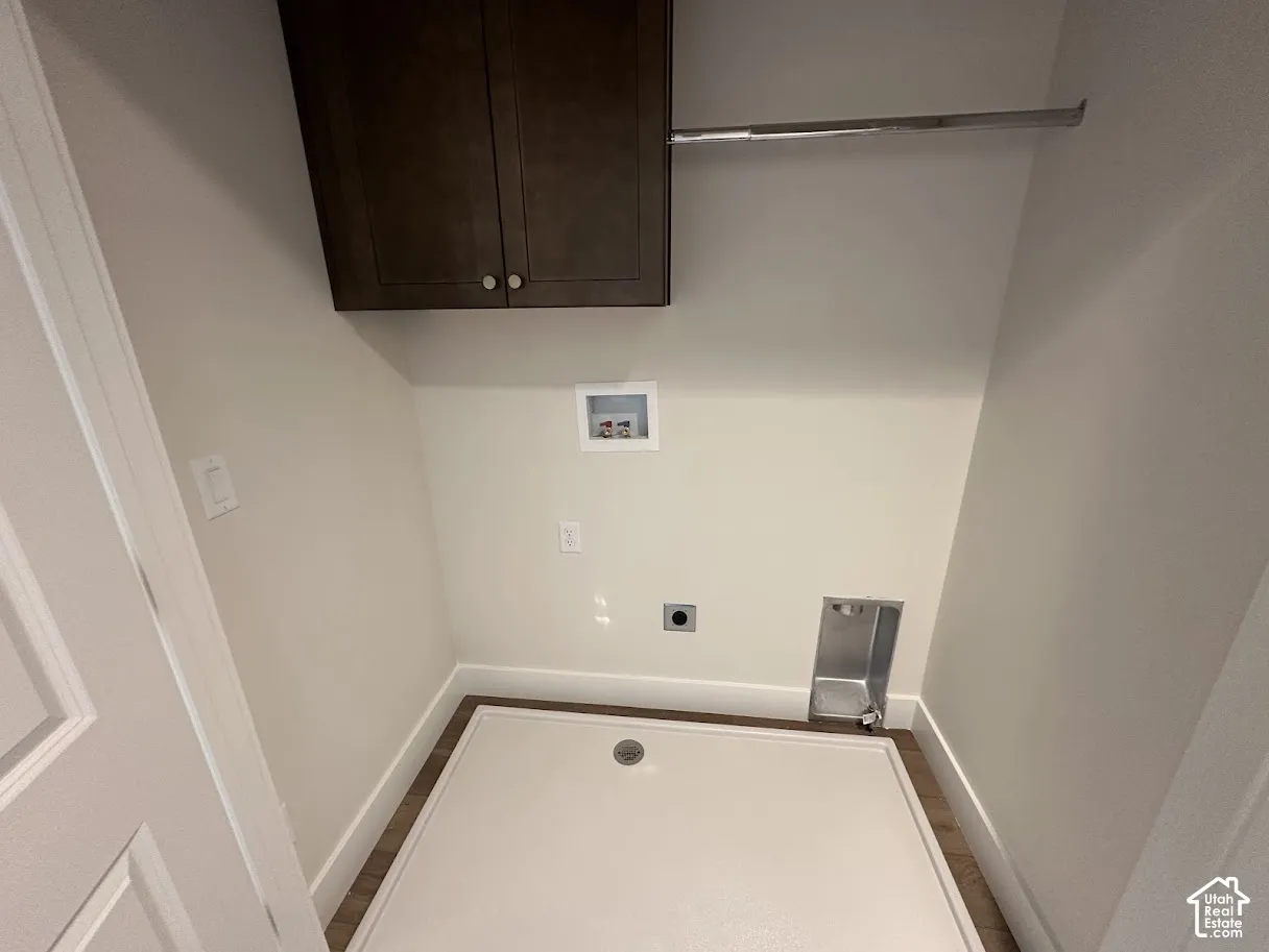 Dedicated laundry space with wood-finish flooring, white baseboards, and neutral wall paint.Picture taken from comparable unit.