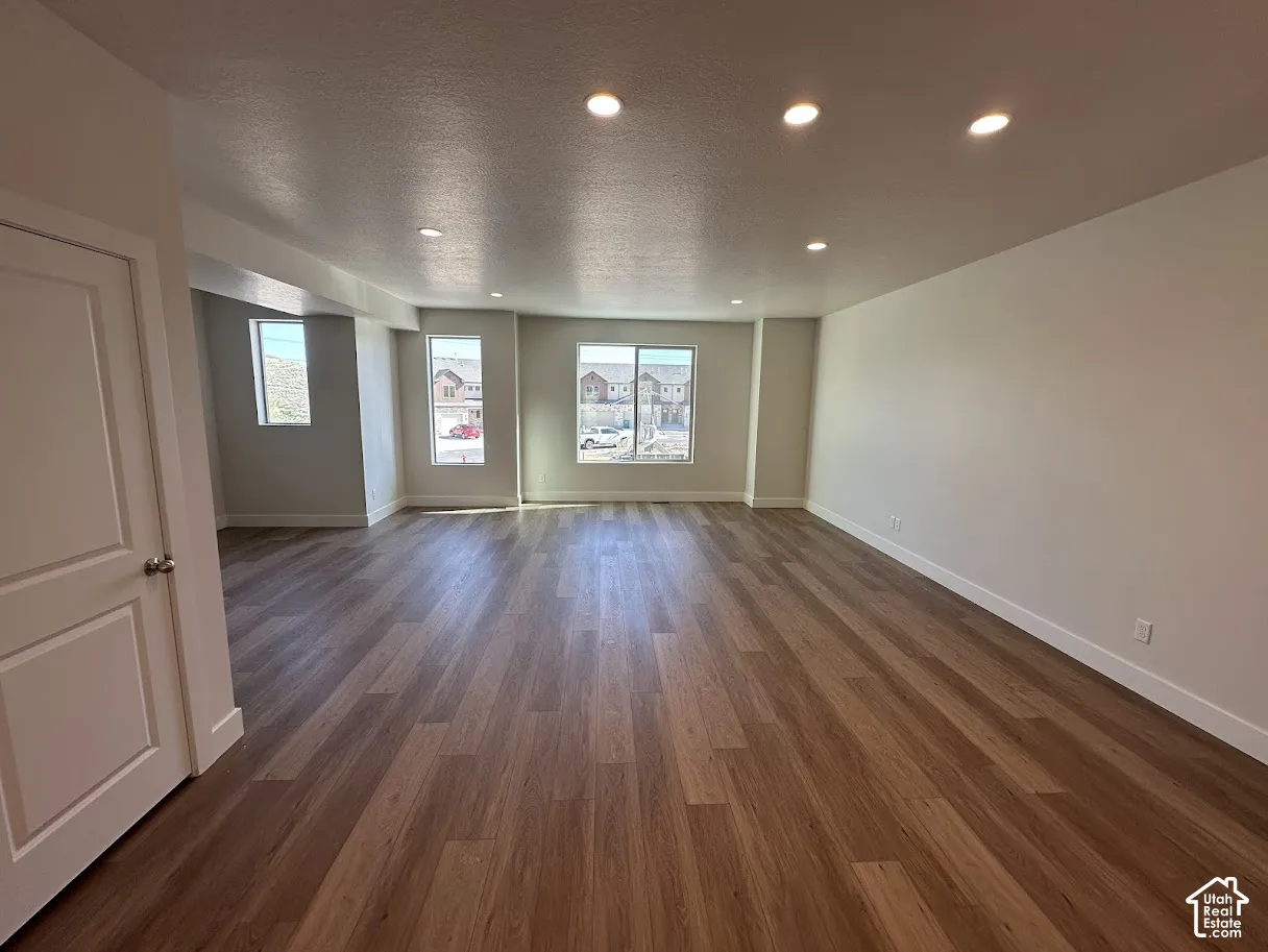 Spacious room featuring wood-finish flooring, recessed lighting, and multiple windows.Picture taken from comparable unit.