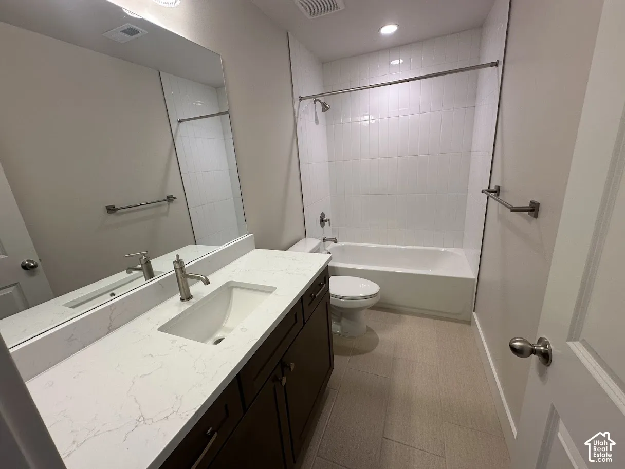 Bathroom featuring a white bathtub, a single vanity with a white countertop and integrated sink, dark wood-finish cabinetry, and light-toned floor tiling.Picture taken from comparable unit.