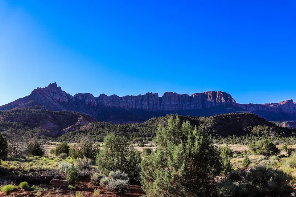 Expansive mountain scenery featuring rugged peaks, a prominent mesa, and a clear blue sky