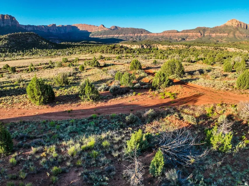 Expansive land parcel featuring desert landscaping, red dirt trails, and distant mountain ranges