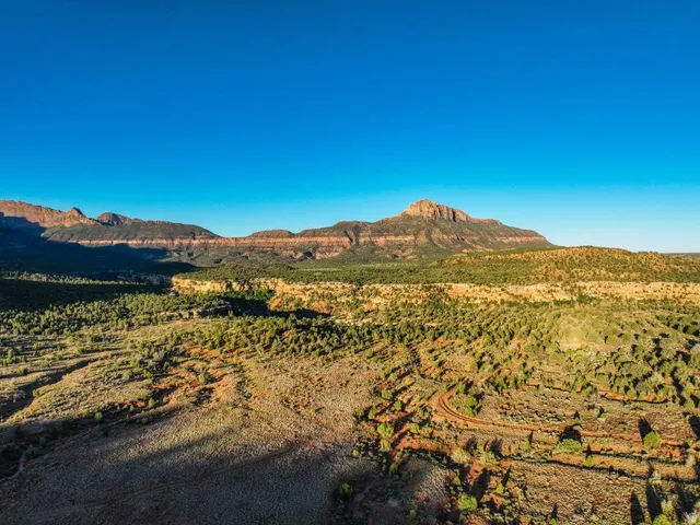 Expansive desert landscape with natural terrain and distant mountains under a clear sky