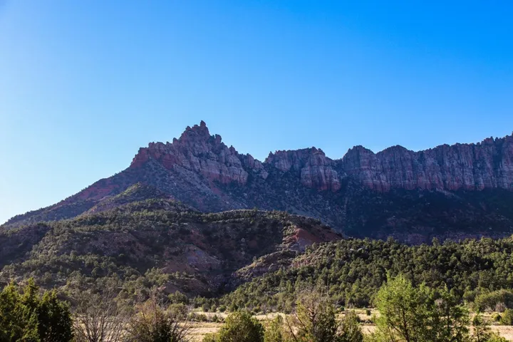 Towering ridgeline featuring red rock formations and evergreen trees