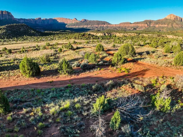 Expansive land parcel featuring desert landscaping, red dirt trails, and distant mountain ranges