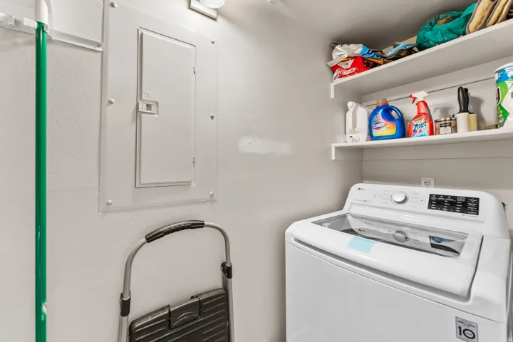 Dedicated laundry space featuring a built-in top-load washing machine and white floating shelves for storage