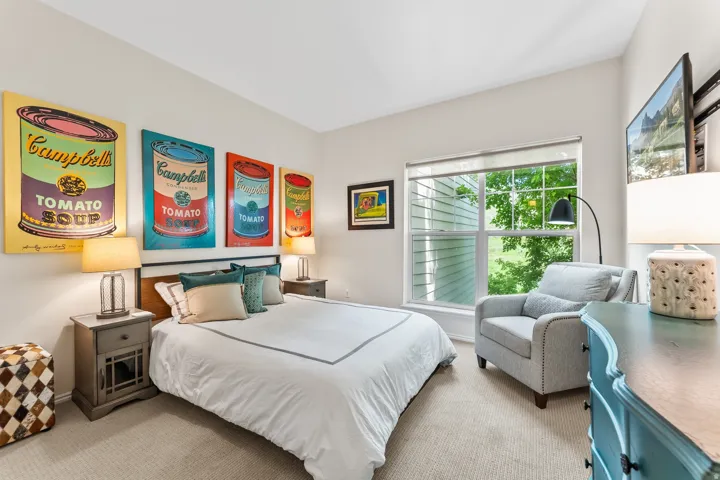 Carpeted room featuring a large window, neutral wall paint, and a built-in mounted television