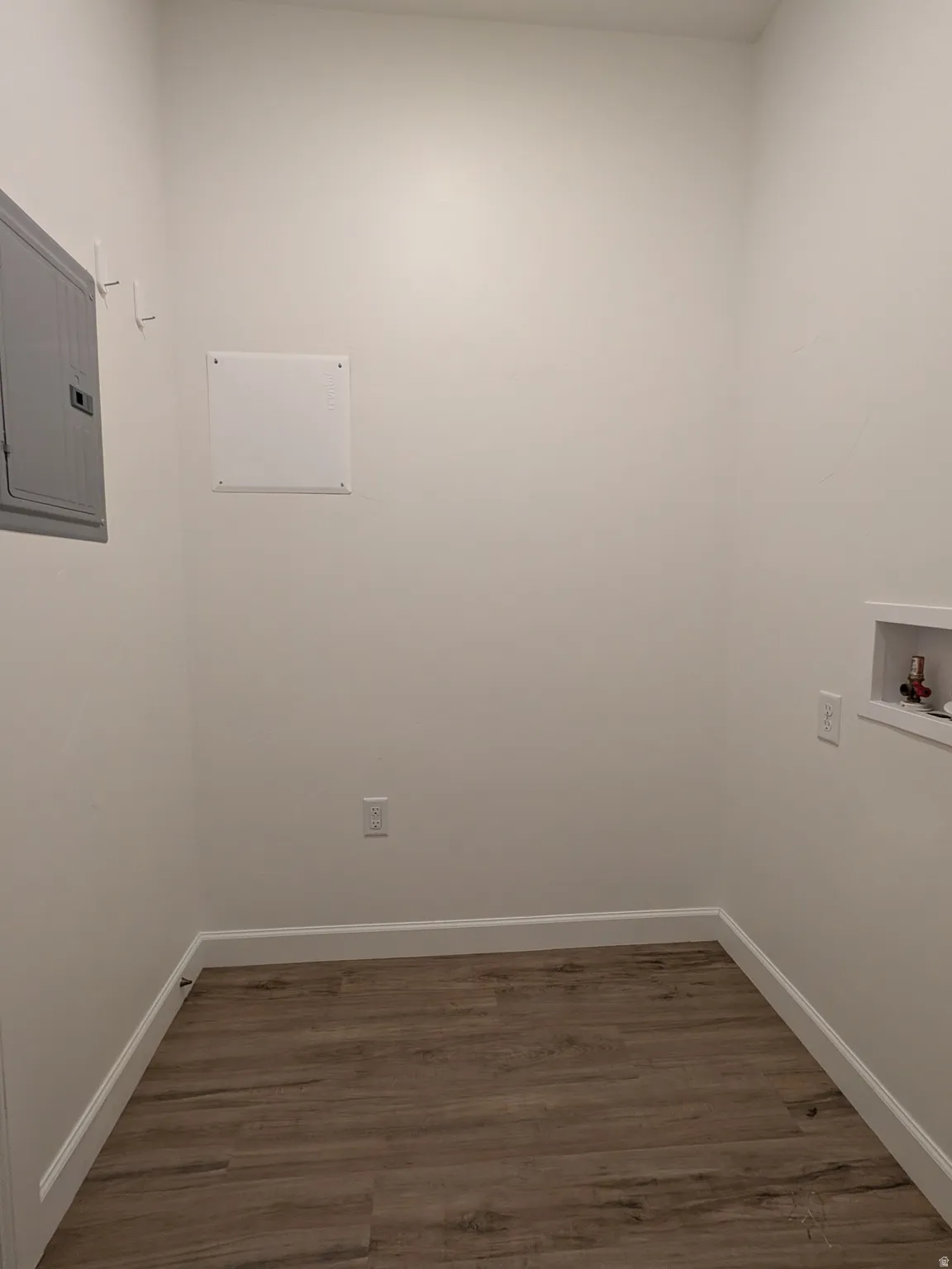 Laundry area with dark wood finished floors, electric panel, and hookup for a washing machine