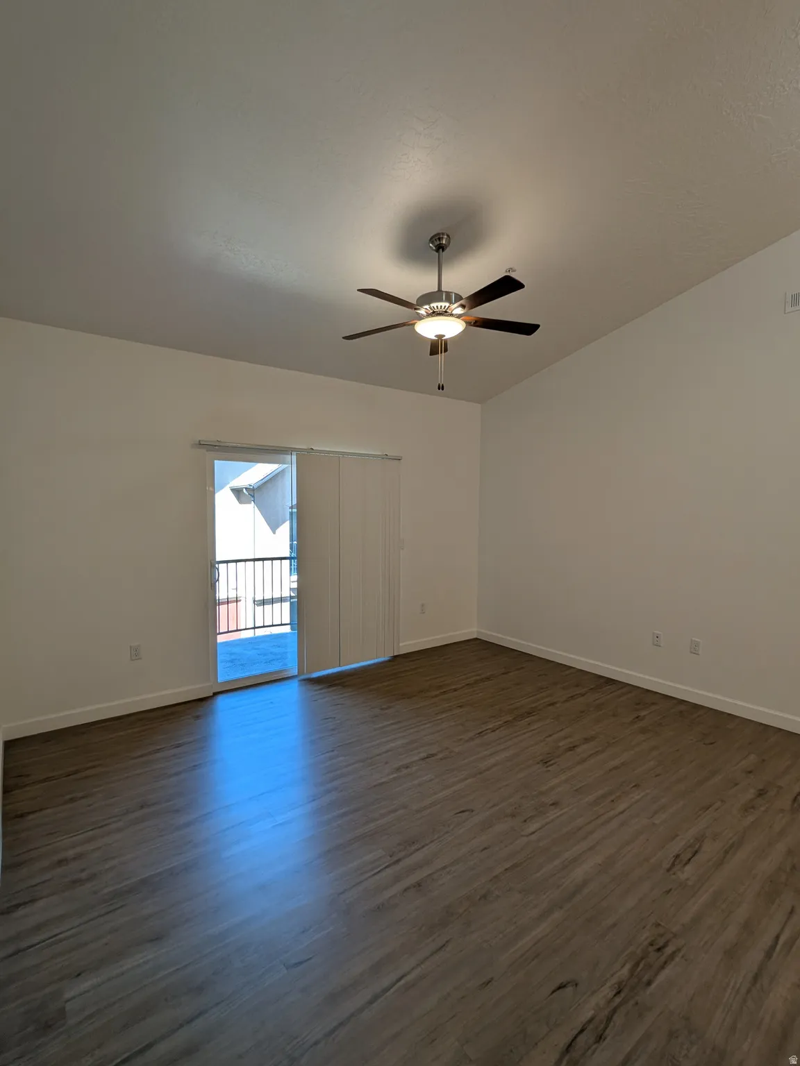 Empty room with dark wood-style flooring and ceiling fan