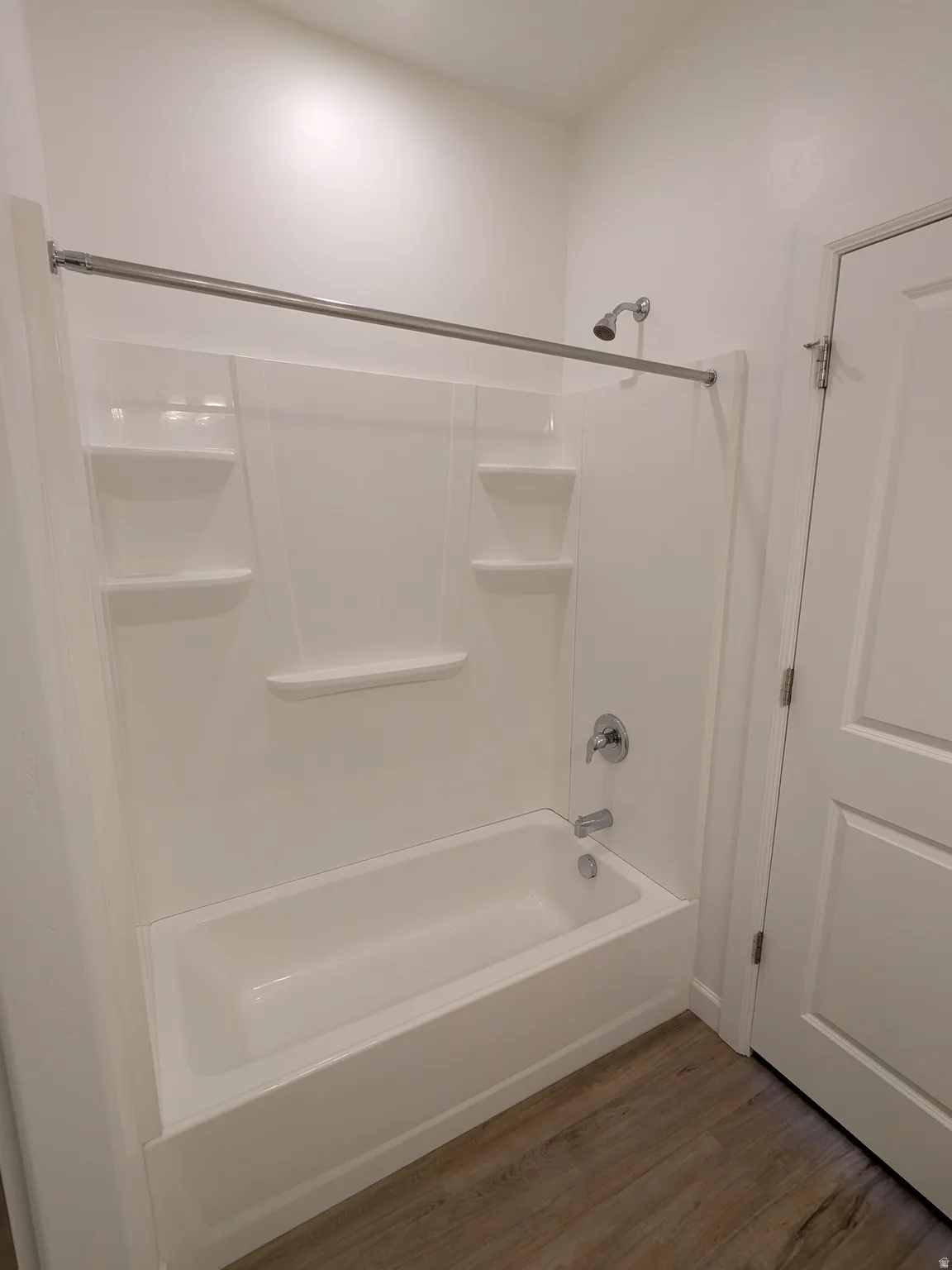 Full bath with dark wood-style flooring and tub / shower combination