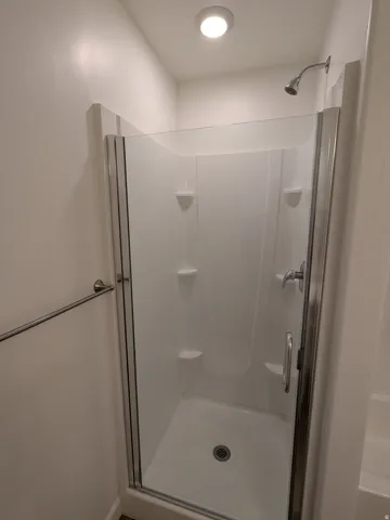 Full bath featuring a stall shower and baseboards