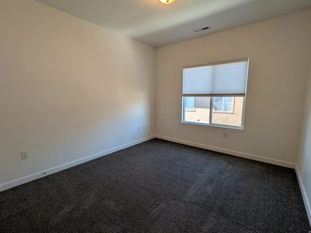 Unfurnished room with dark carpet and baseboards