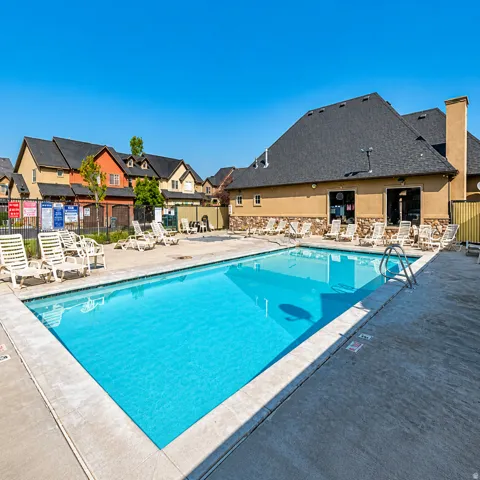 Community swimming pool featuring a concrete deck and multiple lounge chairs