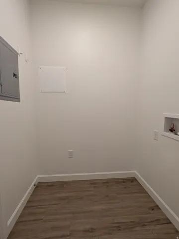Laundry area with dark wood finished floors, electric panel, and hookup for a washing machine