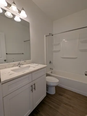 Bathroom featuring vanity, shower / bathtub combination, and dark wood-style floors