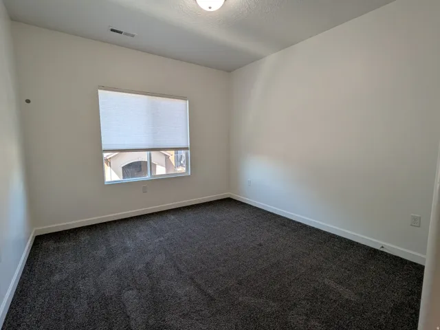 Unfurnished room featuring dark carpet and a textured ceiling