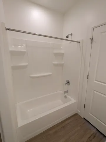 Full bath with dark wood-style flooring and tub / shower combination
